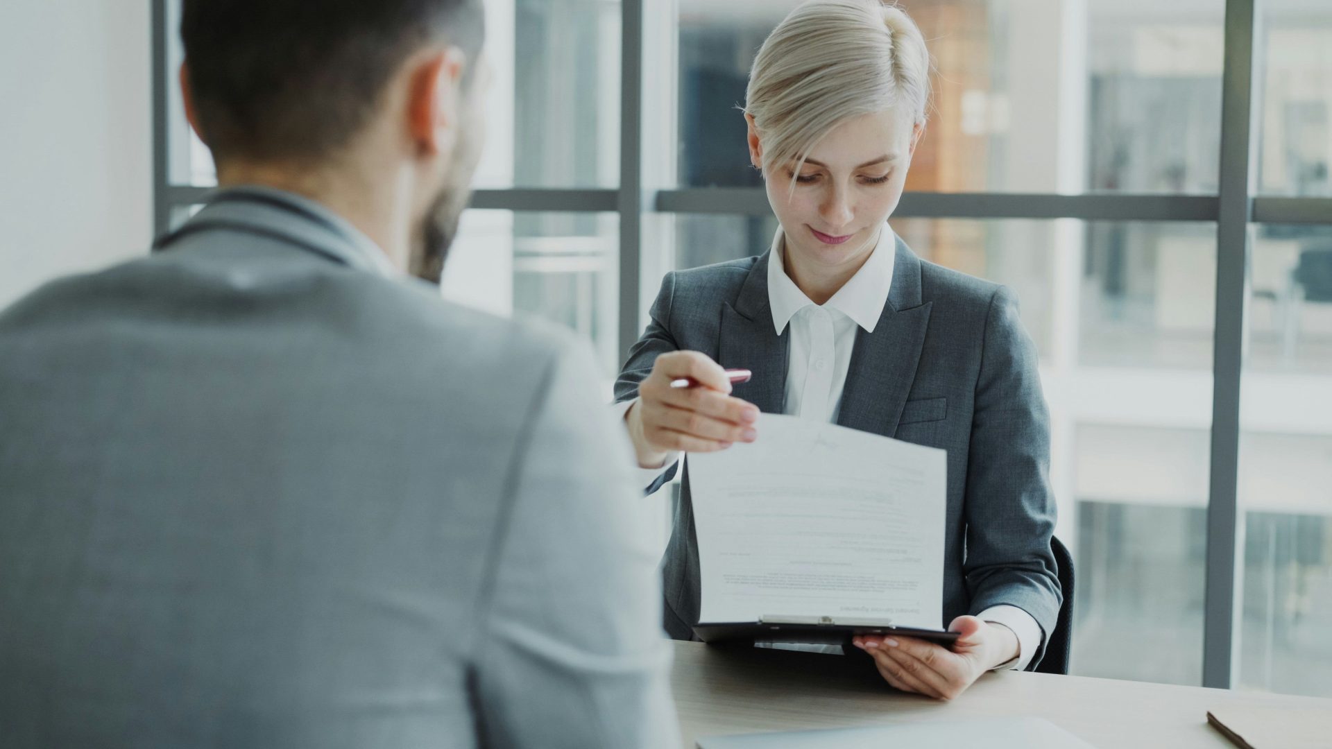 Une femme en tailleur montre un document à un homme