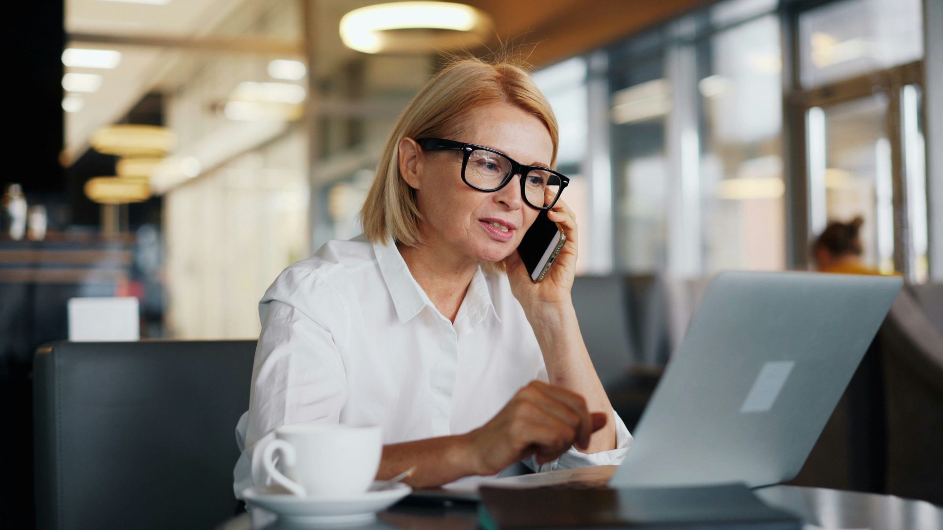 une femme assise à une table parle au téléphone portable