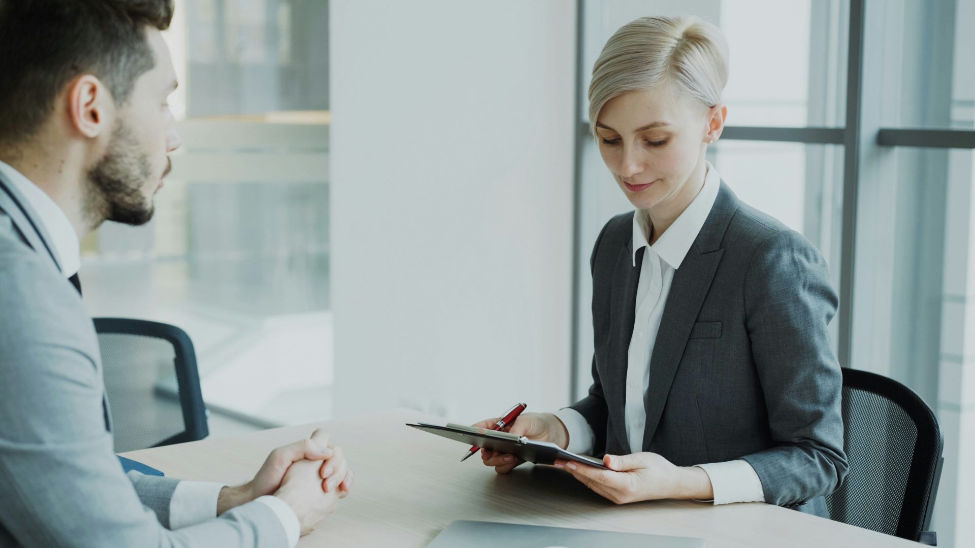 Une femme en tailleur examine un document avec un homme.